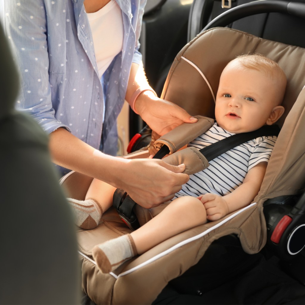Mom buckling baby in a car seat