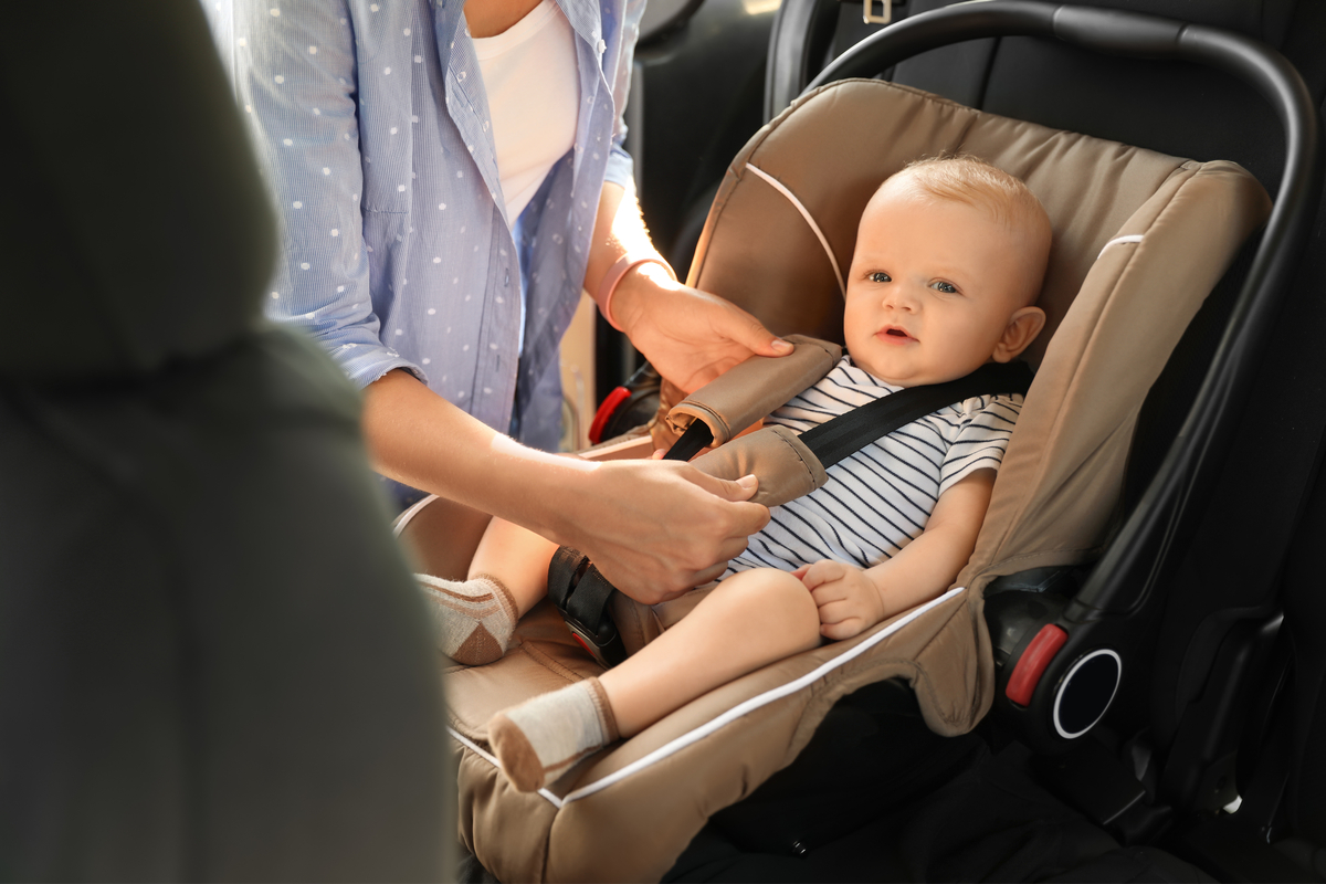 Mom buckling baby in a car seat