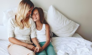 Mother and daughter talking in bed