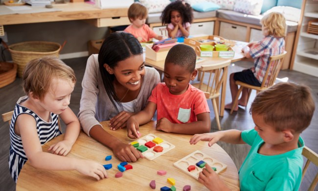 Preschool teacher talking with students at a table