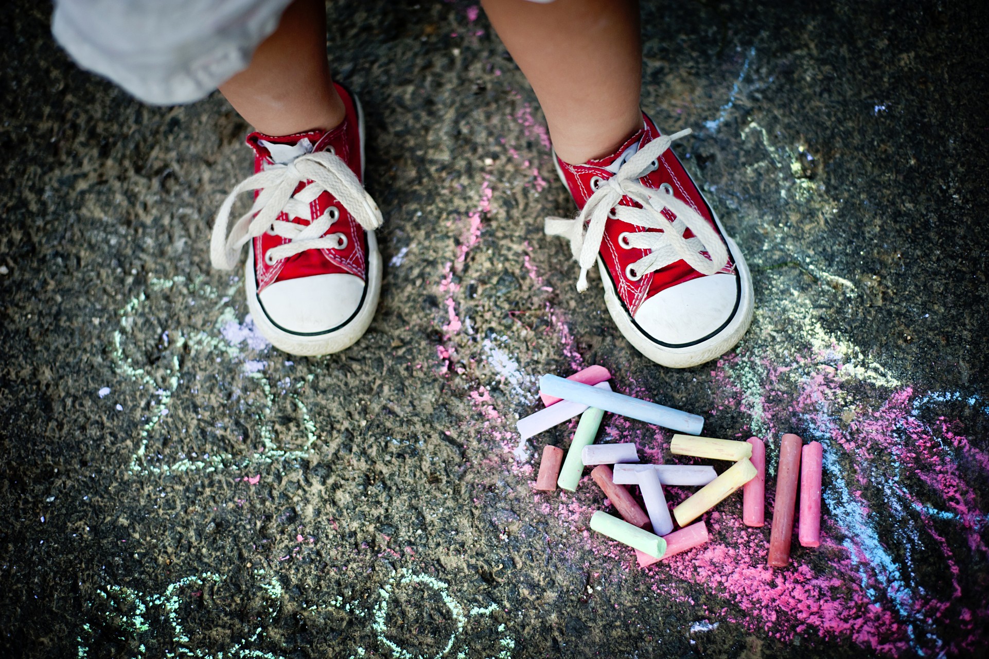 A toddler wearing sneakers outside on concrete