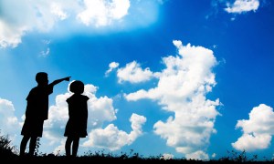 Two kids looking up at cloud shapes