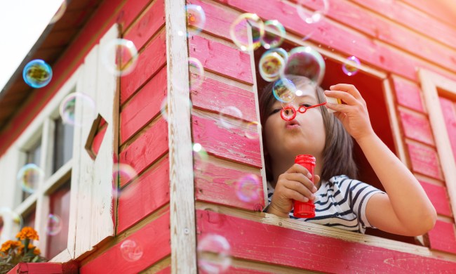 Child blowing bubbles in a playhouse