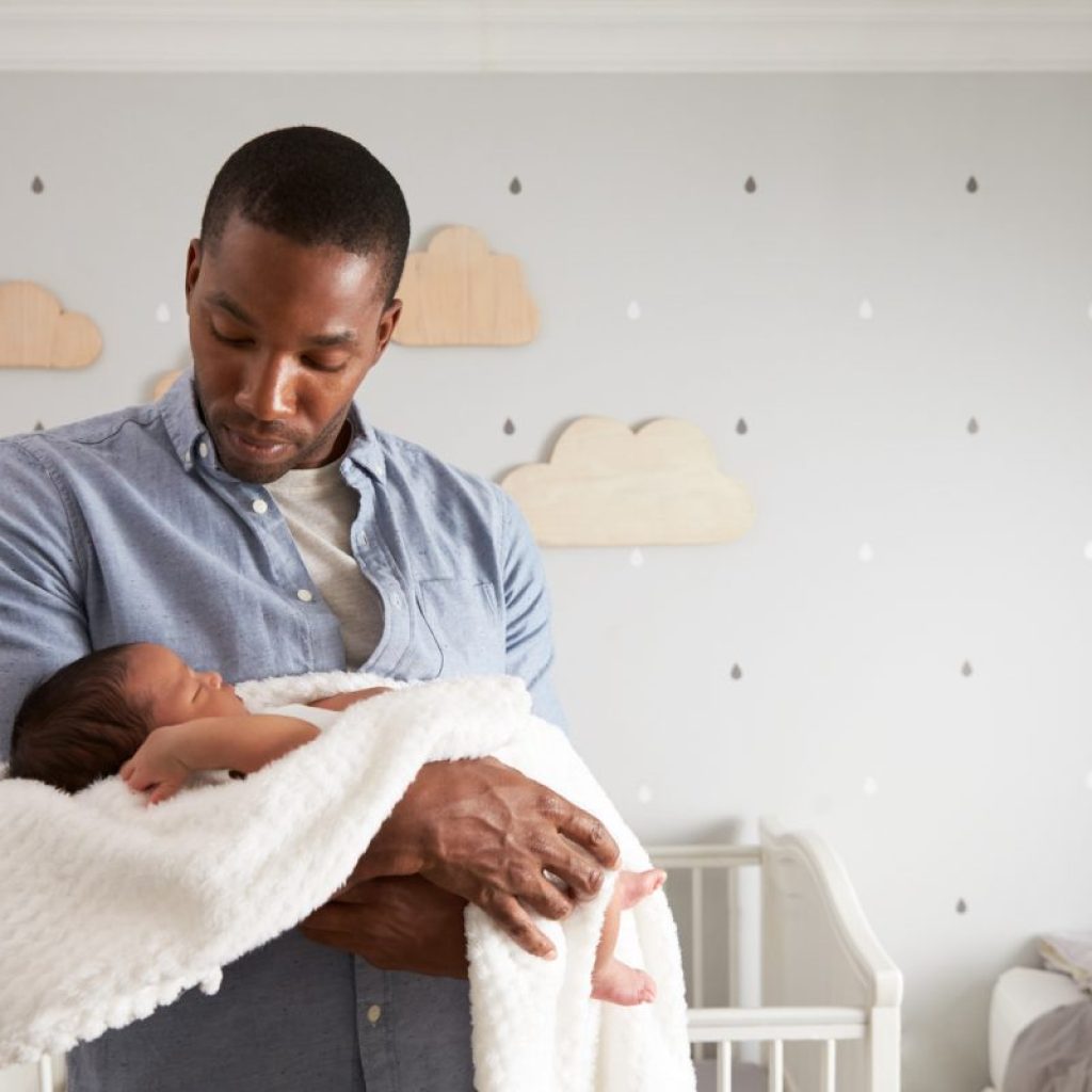 Dad holding baby in the nursery.