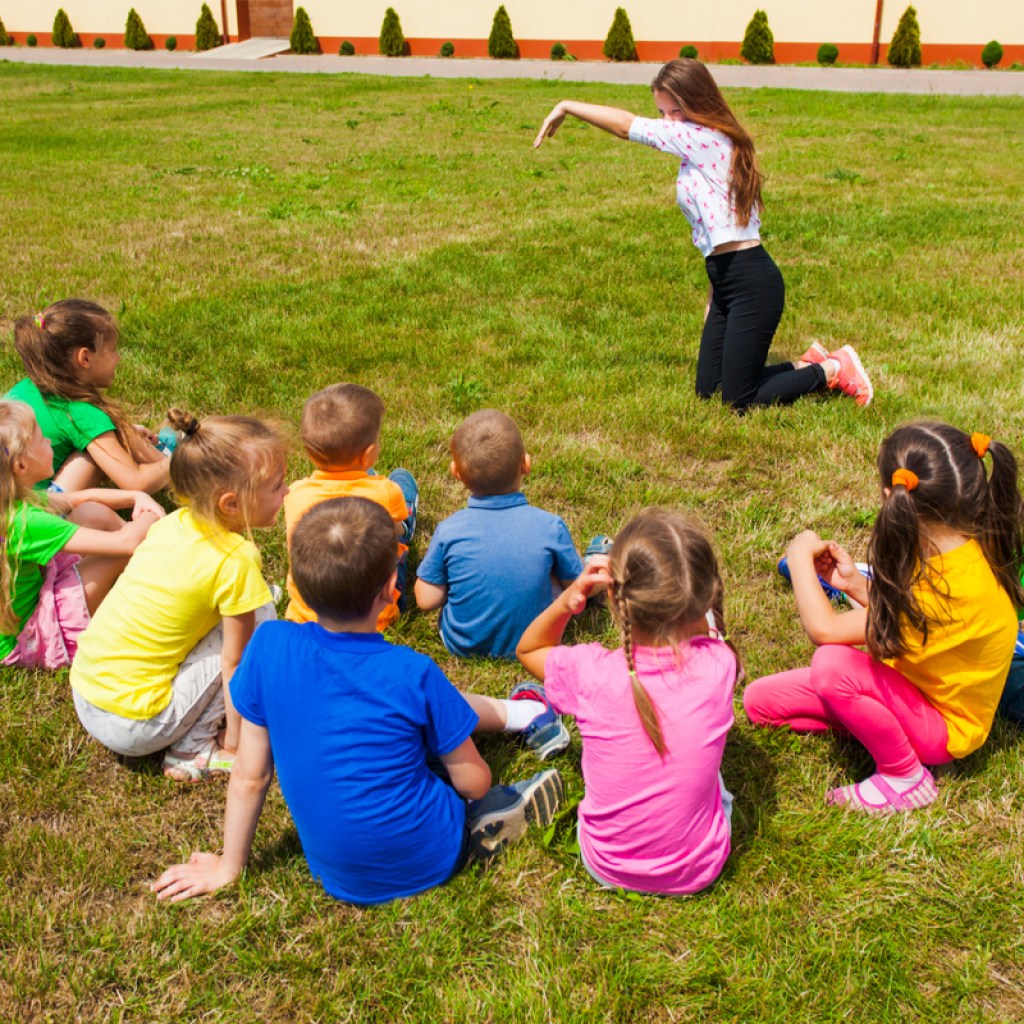 group of kids outside playing an improv game with an adult