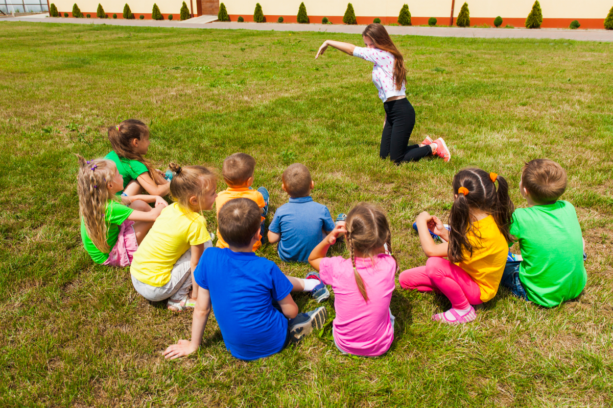group of kids outside playing an improv game with an adult