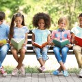 Five kids reading on a bench outside