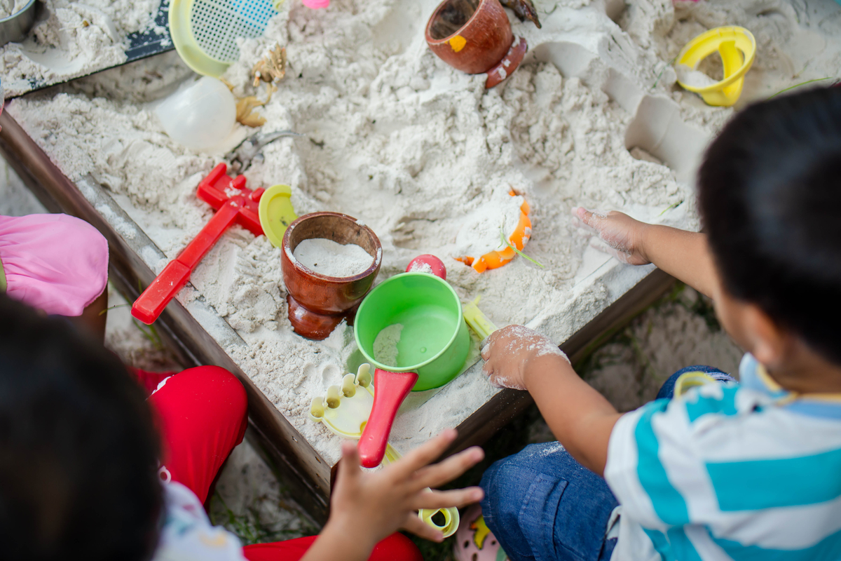 Toddlers playing in sand at summer birthday party