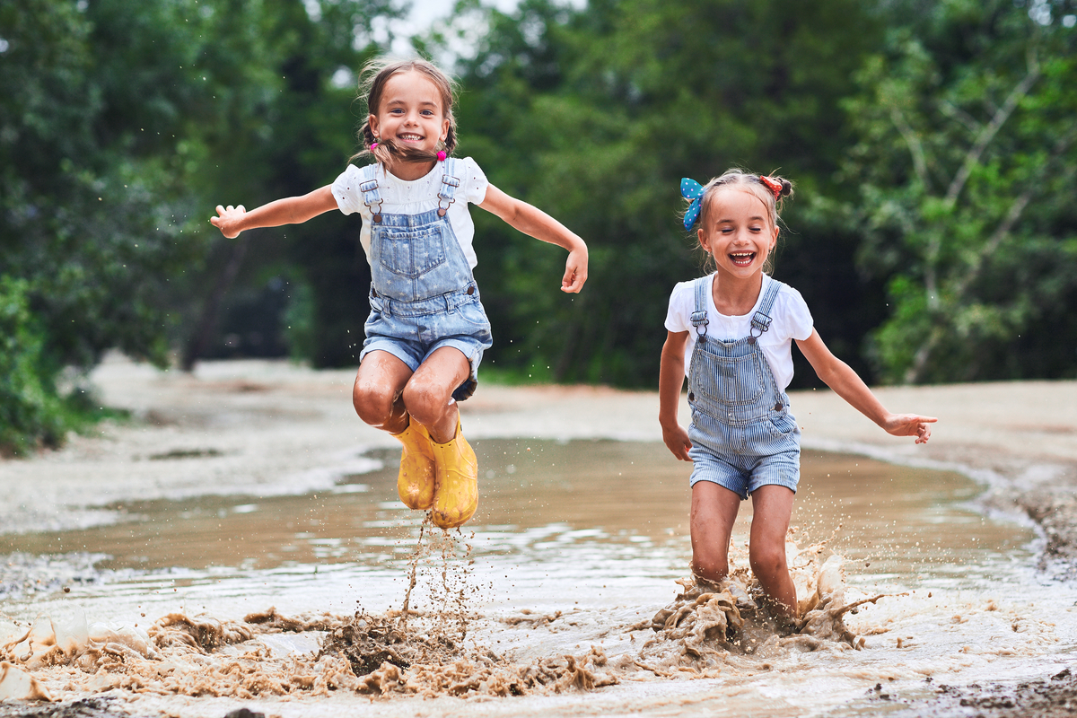 Twin girls enjoying puddle jumping in the summer