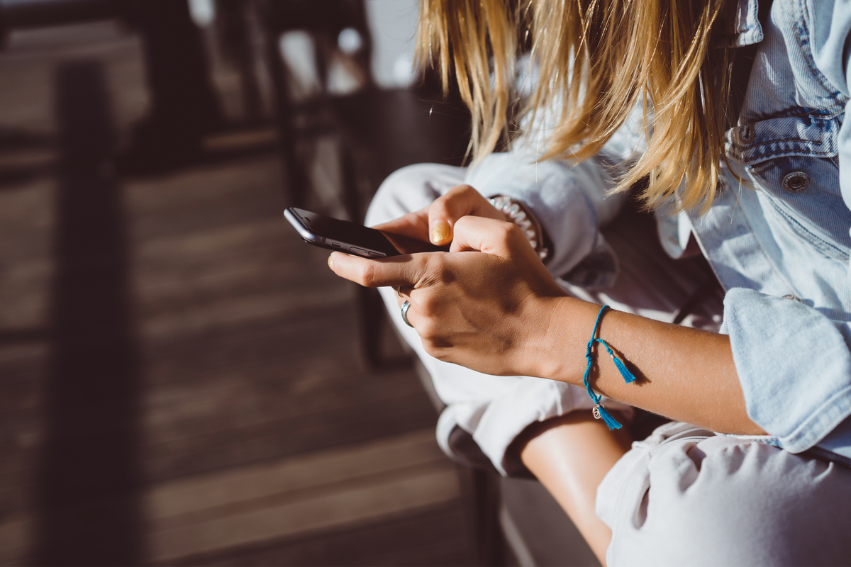 Young woman having fun on her iPhone outside on a sunny day