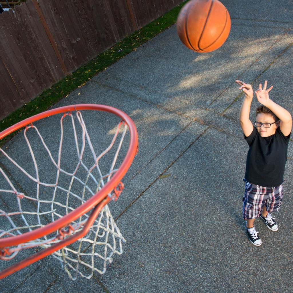Boy shooting baskets in his backyard