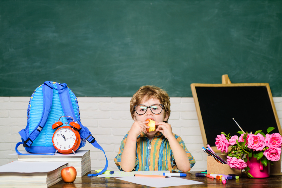 Kindergarten boy eating an apple as a snack