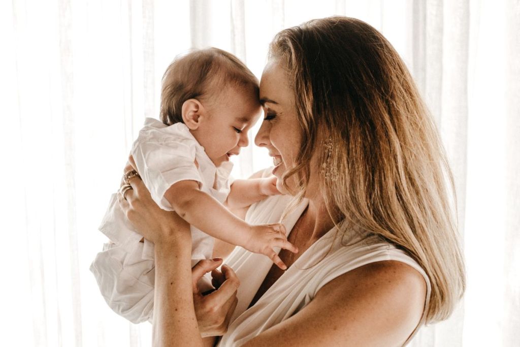 Mom holding her baby up to her face.