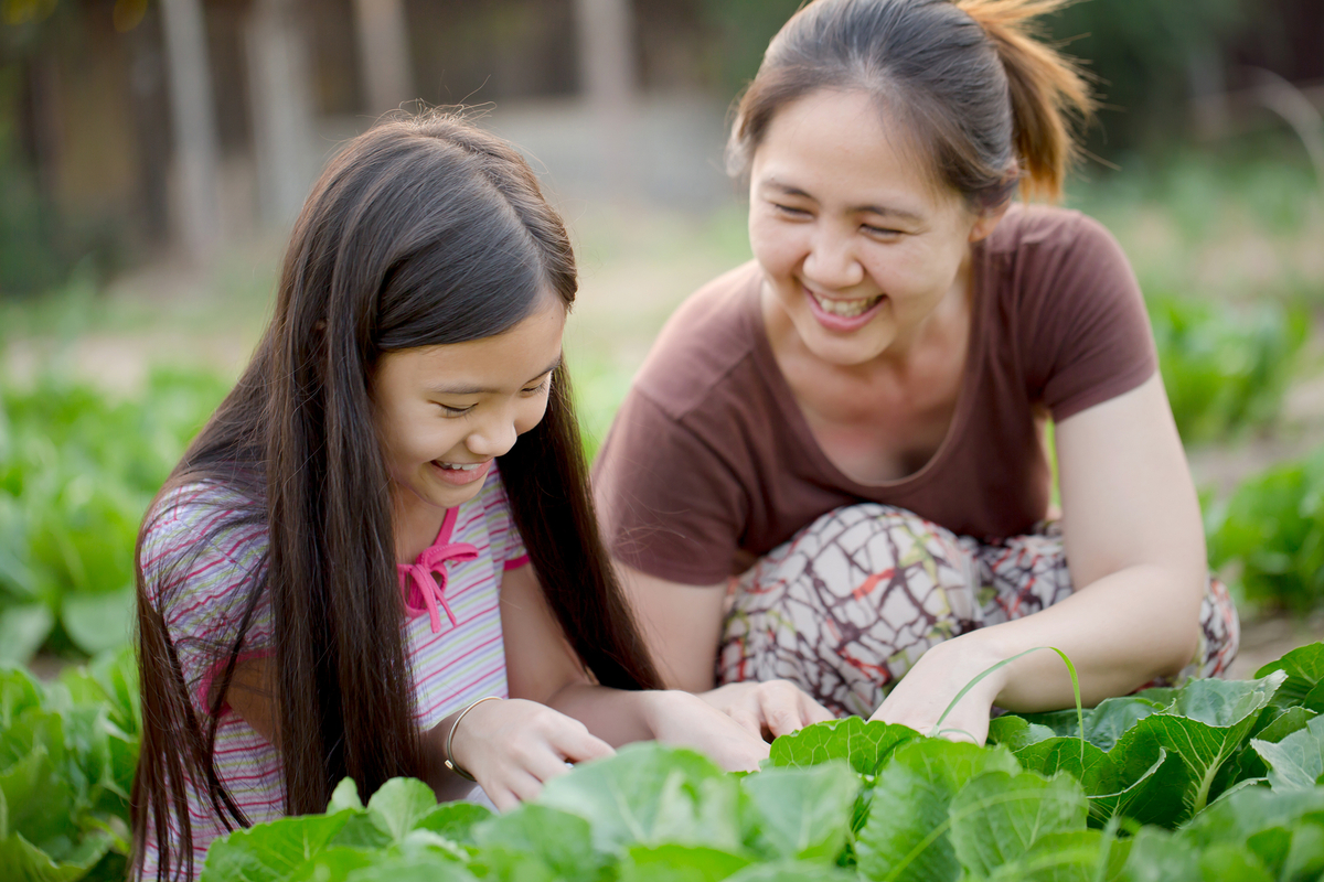 mom and daughter tending to vegetables in garden