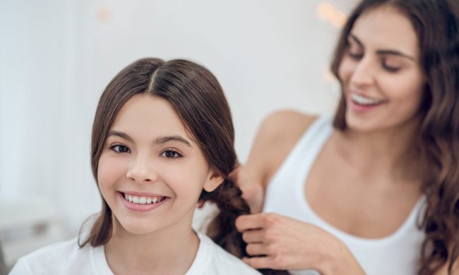 Mom fixing daughter's hair and putting it in braids