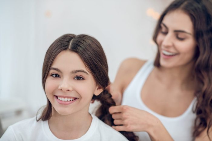 Mom fixing daughter's hair and putting it in braids
