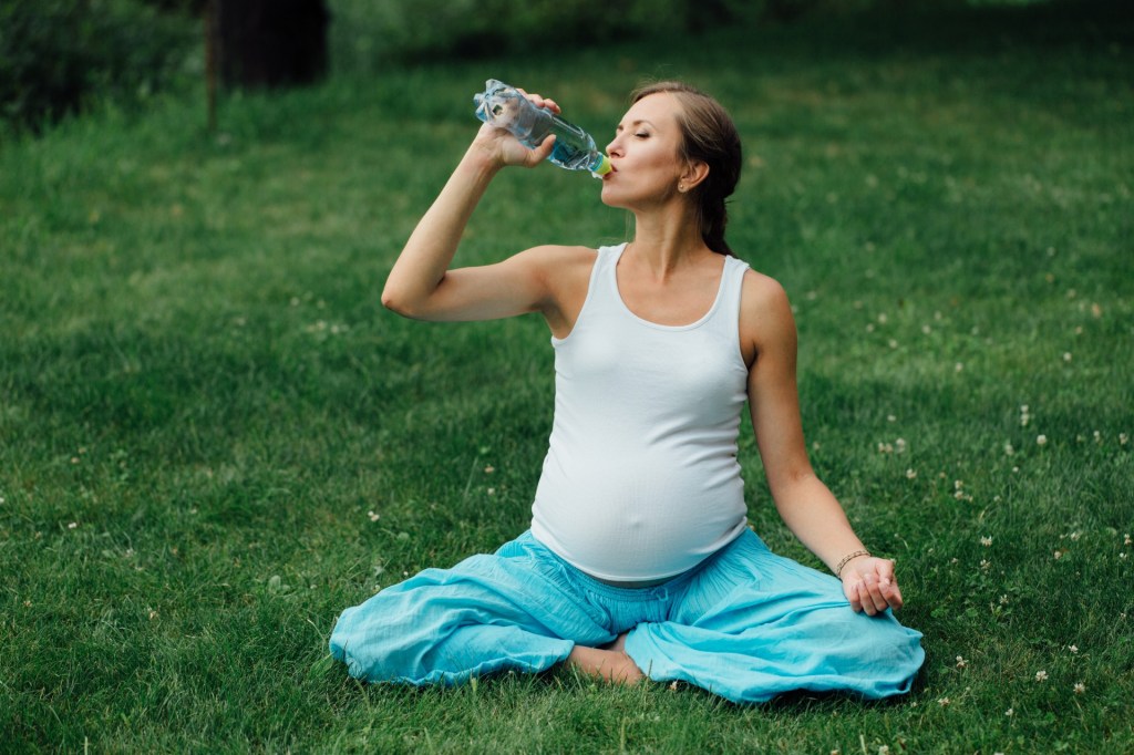 pregnant woman drinking a bottle of water