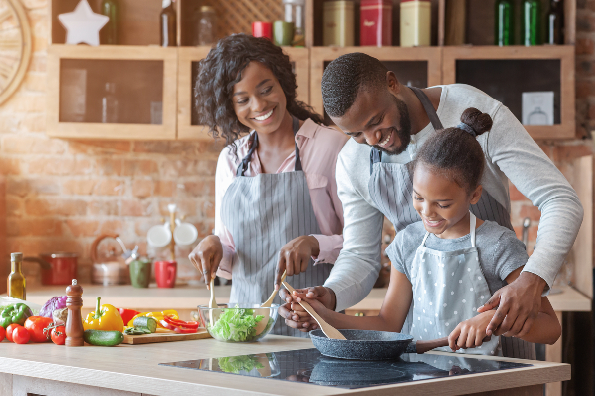 parents teaching their daughter how to cook