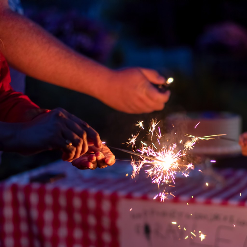 Woman lighting a sparkler on Fourth of July