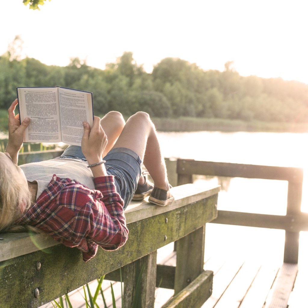 Teen girl enjoying a summer read on a dock