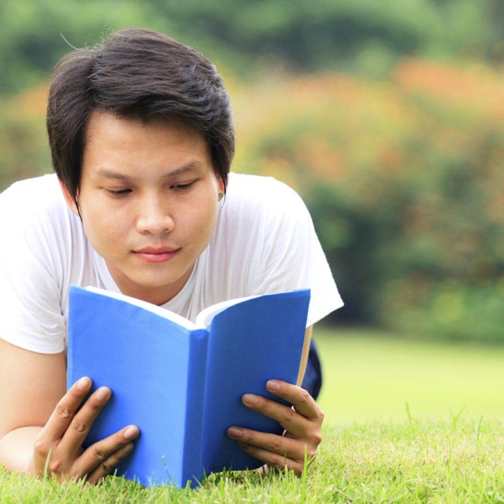 teen boy reading in the grass