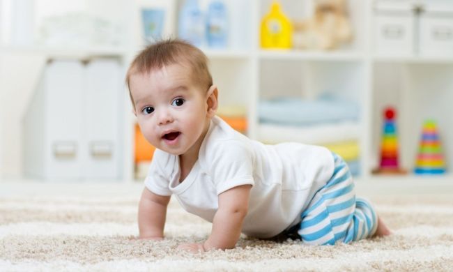 Cute baby crawling across a rug.