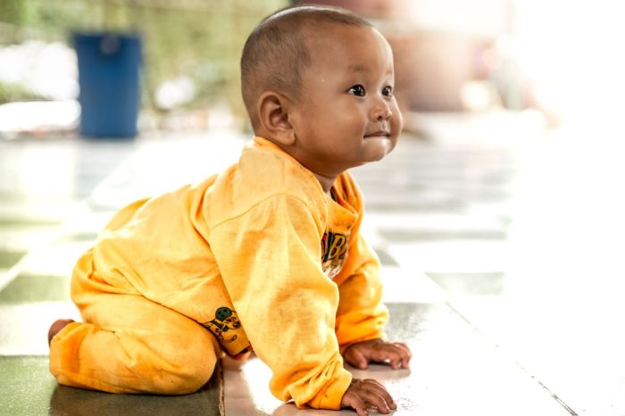 baby in yellow outfit crawling
