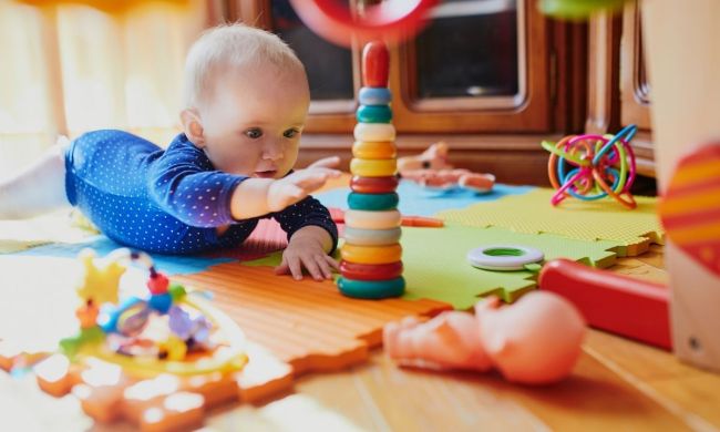 Baby playing on tummy and reaching for a toy