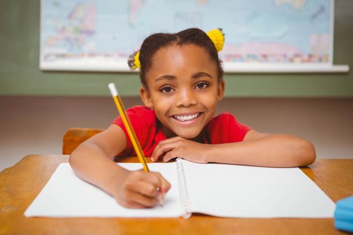 Child smiling and writing in a notebook