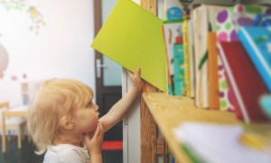 child pulling book off shelf