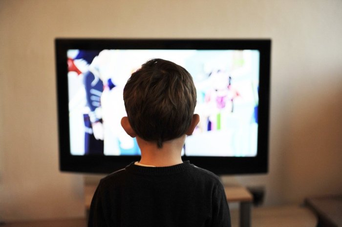child standing in front of tv