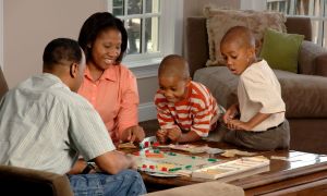 Parents with children playing a board game.