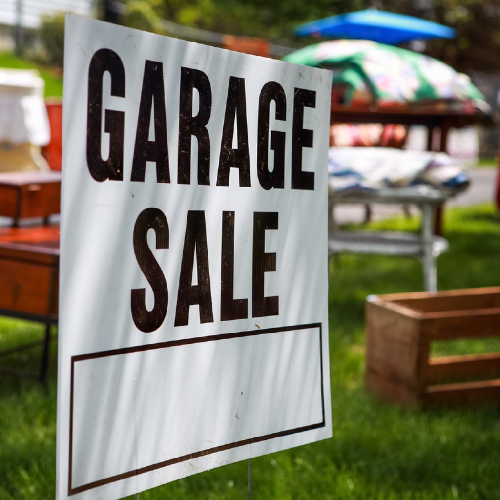 garage sale sign with items for sale behind it