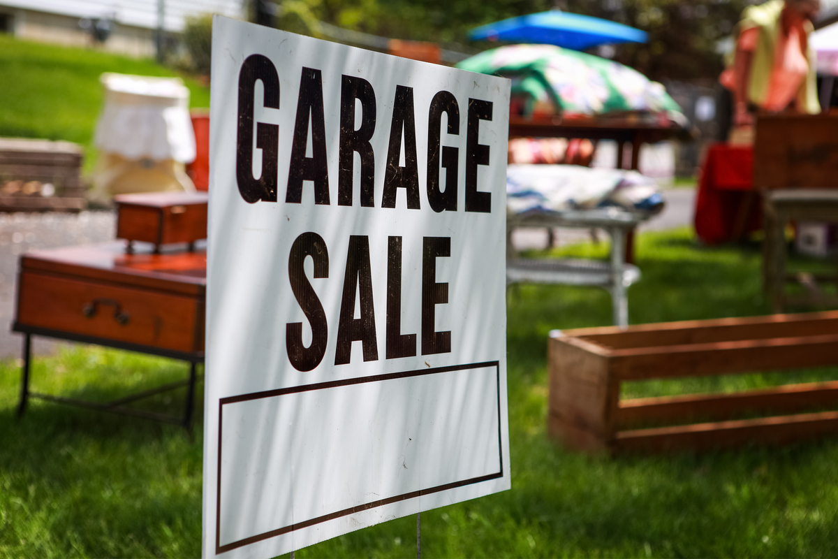 garage sale sign with items for sale behind it