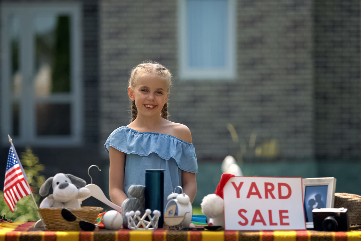 young girl selling her old toys at a garage sale