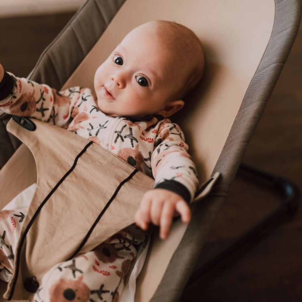 baby wearing sleeper in a bouncer