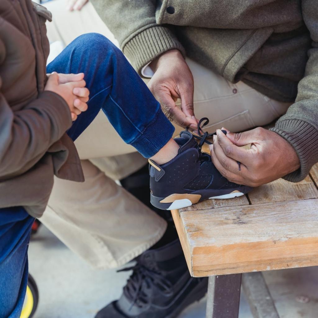 parent teaching a child how to tie shoes