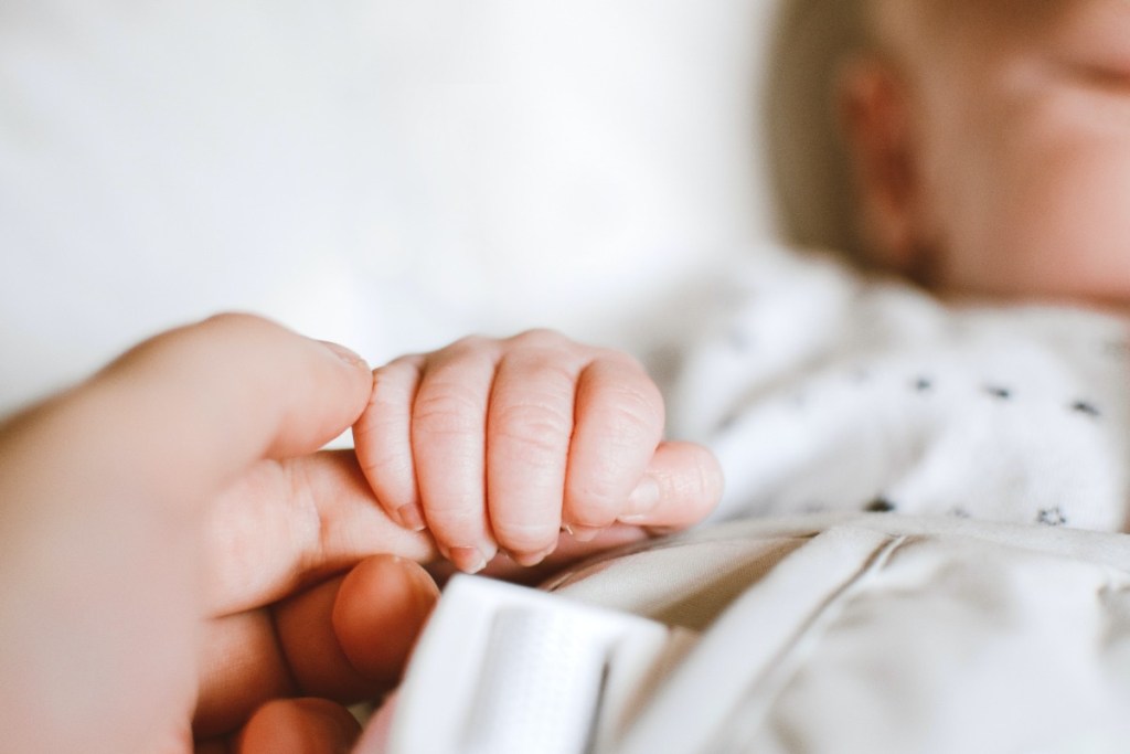 a person holding a sleeping baby's hand