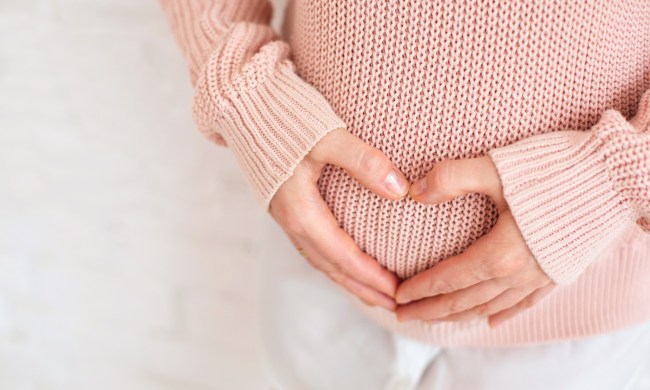 Woman making a heart with hands over Post partum belly