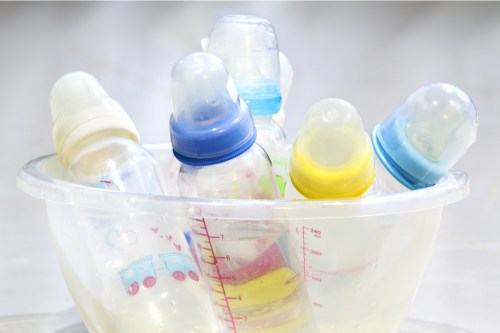 A cluster of different baby bottles in a bowl.