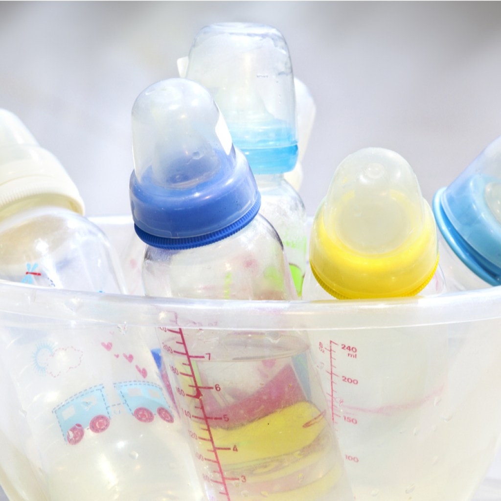A cluster of different baby bottles in a bowl