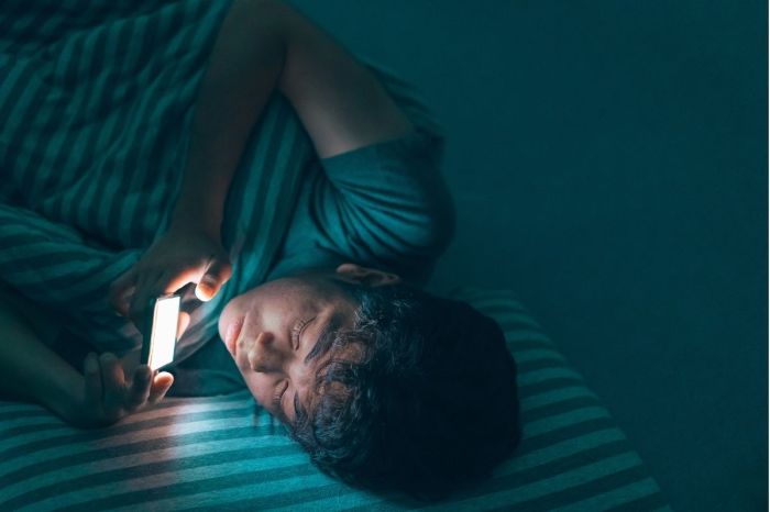 teenagers sleep deprivation teen boy on phone in bed