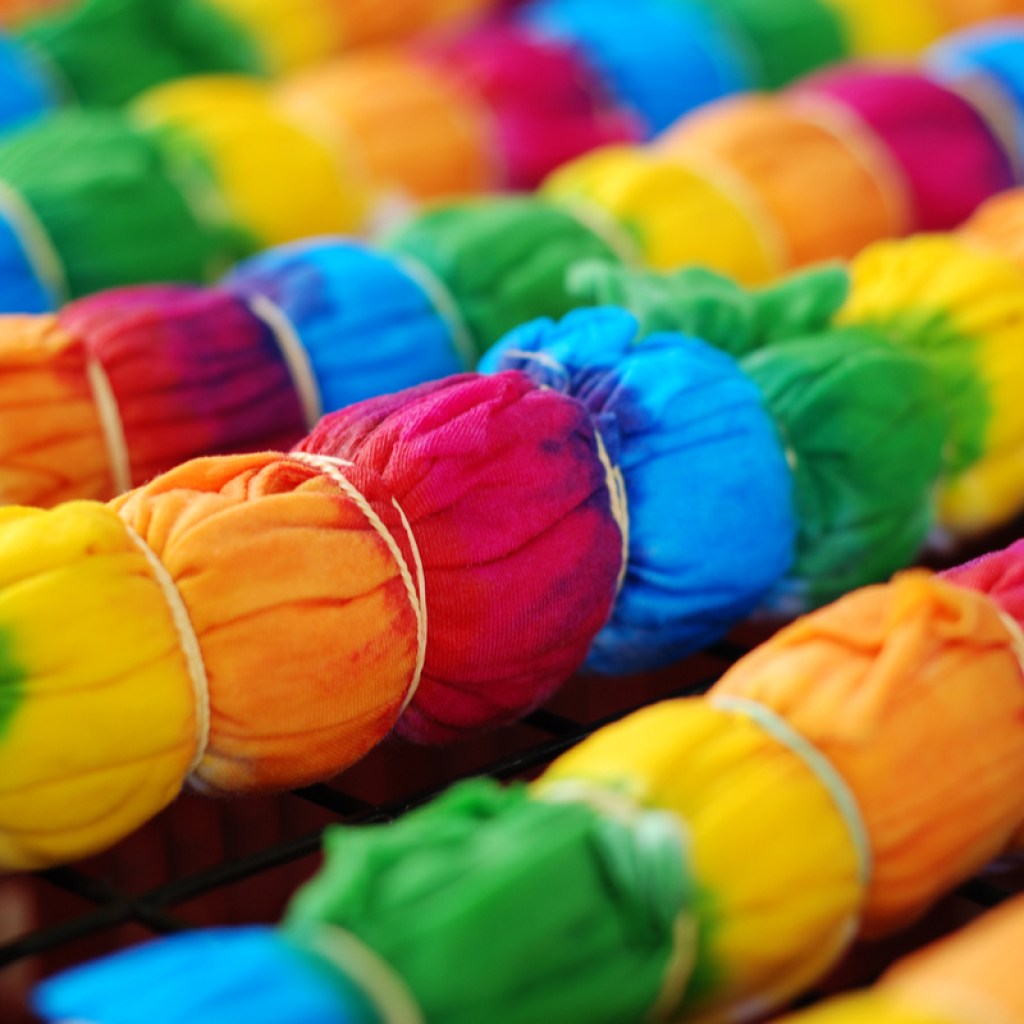Tie-dye shirts with rubber bands waiting to be rinsed.