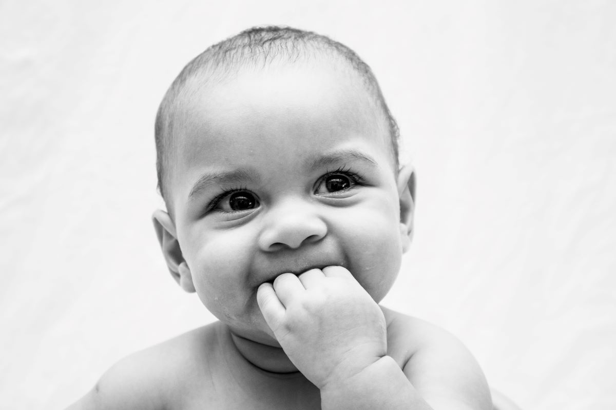 baby chewing on fingers and smiling