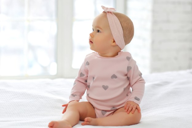 Cute baby girl in a headband sitting up.