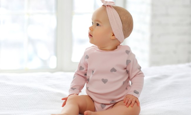 Cute baby girl in a headband sitting up.