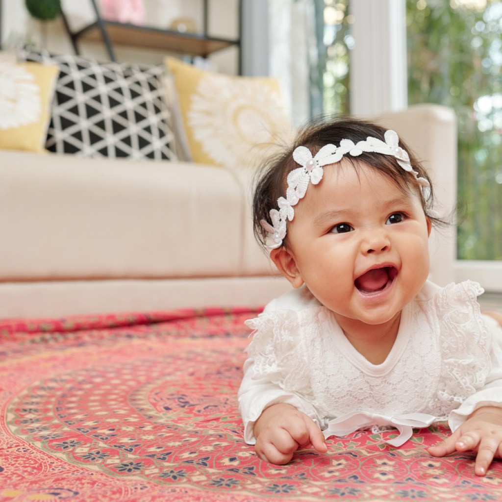 adorable baby playing on the floor in a white headband