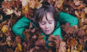 Boy laying in a pile of leaves