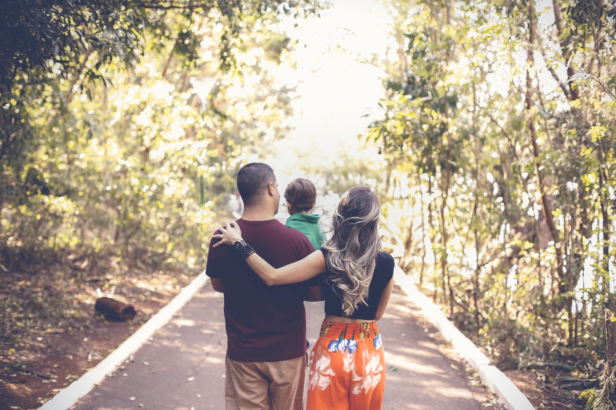 Parents walking down a scenic street holding their child.