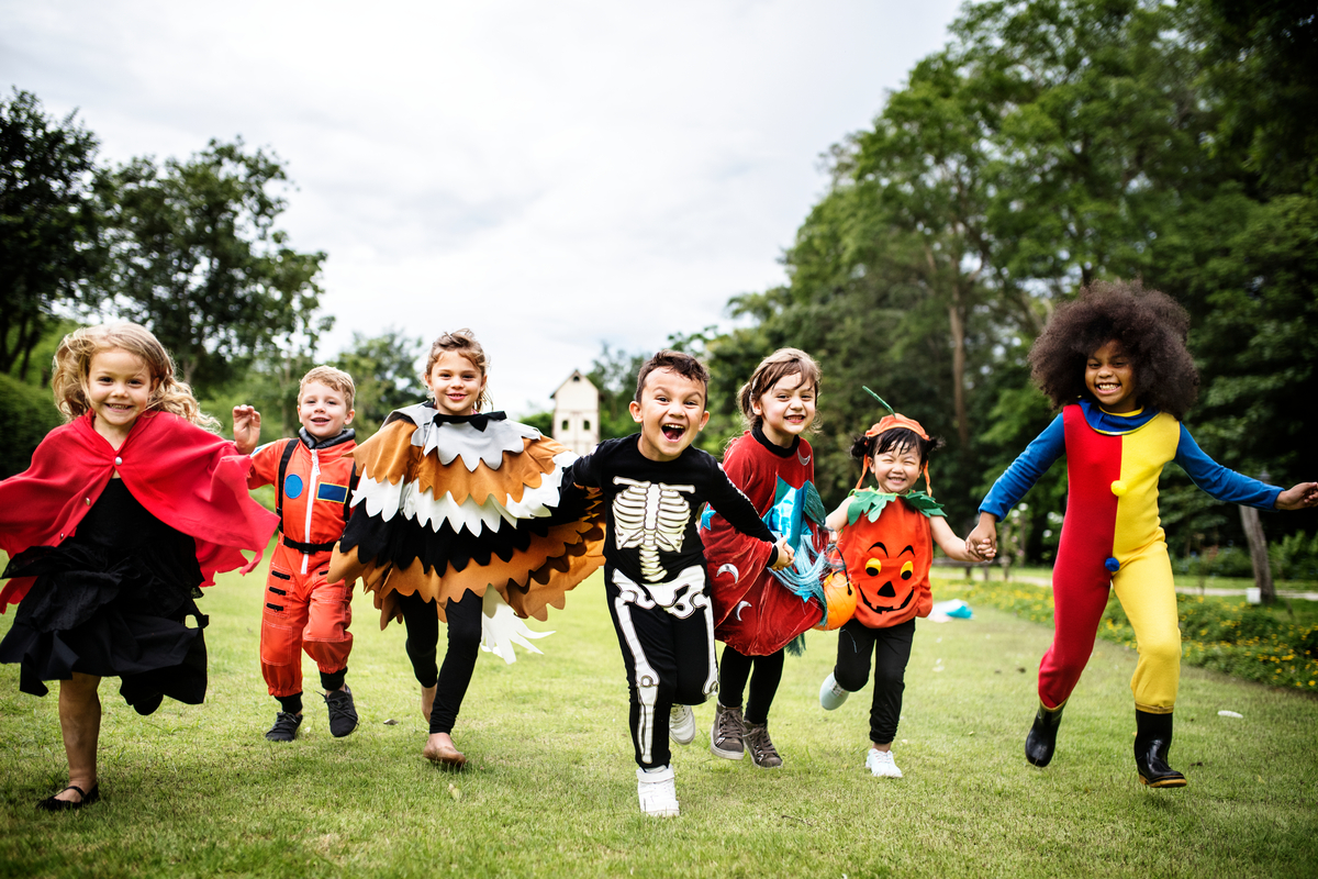 A group of kids in Halloween costumes running outside.